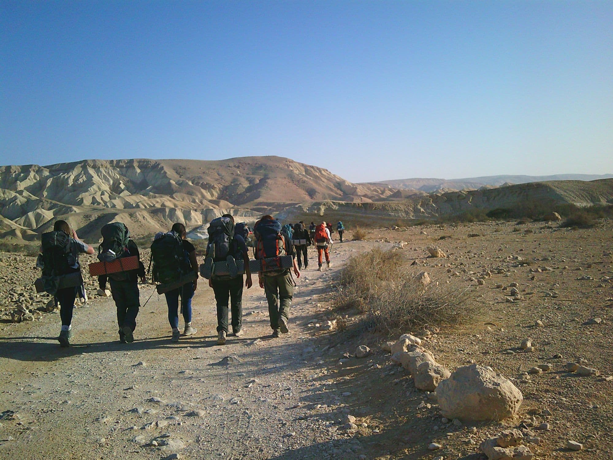 הקבוצה צועדת בשביל מדברי עם תרמילים מלאים